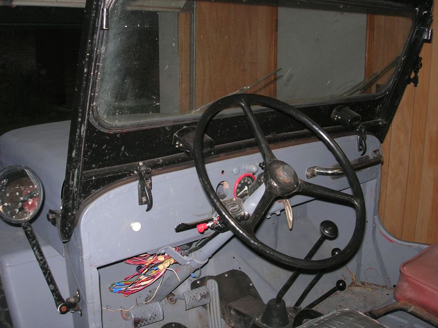 1954 Jeep interior with gray painted dashboard, black steering wheel, and exposed wiring