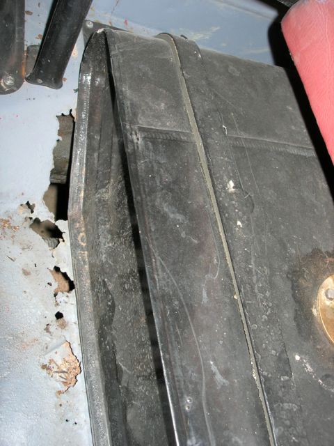 1954 Jeep Wrangler - Close-up view of a vehicle's interior, showing rusted metal and a black component, possibly a fuel tank strap.