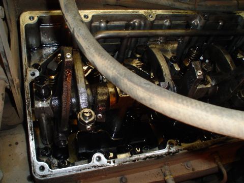 1966 International School Bus - Close-up of an engine's internal components, including the valve train and crankshaft, covered in oil.