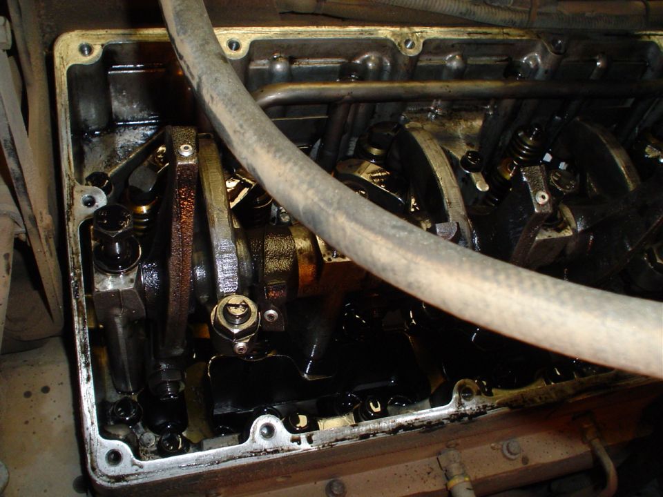 Open diesel cylinder head with rocker arms and valve springs, hose draped across