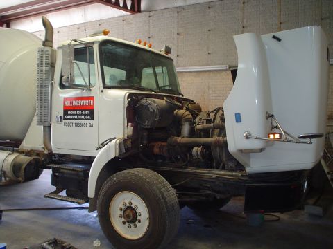 1966 International School Bus - A white cement mixer truck is parked inside a garage with its hood open, revealing the engine compartment.