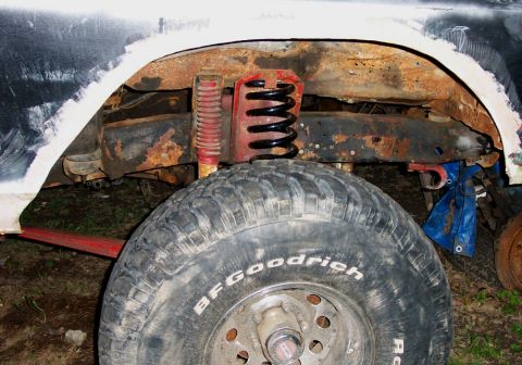1978 Ford Bronco - Close-up of the rear suspension and tire of a vehicle, showing significant rust and modifications.