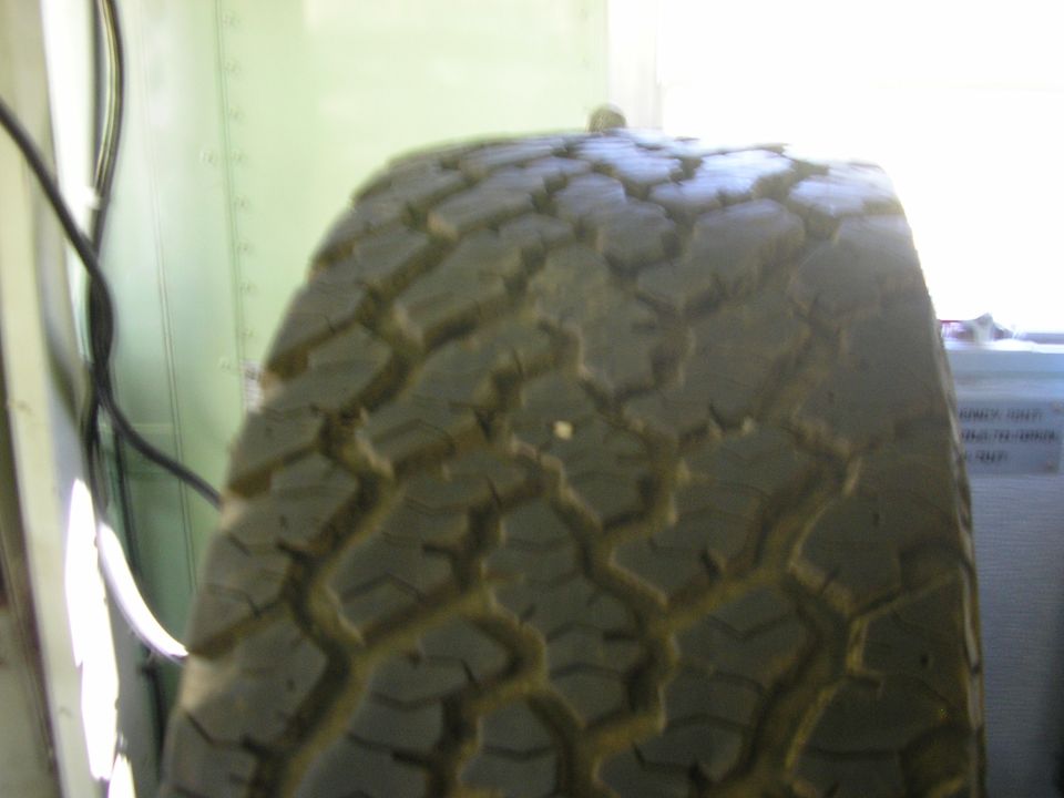 close-up of a tire tread with a black cable on the left and a white wall behind