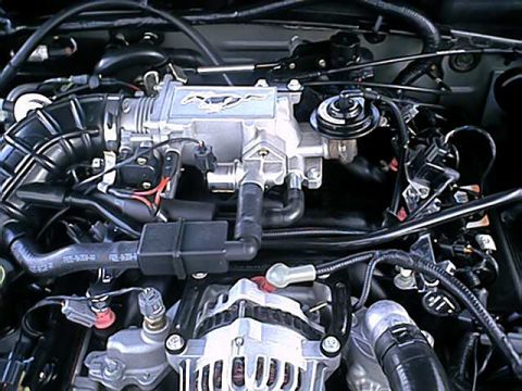 2004 Ford Mustang - The engine bay of a 2004 Ford Mustang shows a silver intake manifold with a running horse emblem and various hoses and wires.