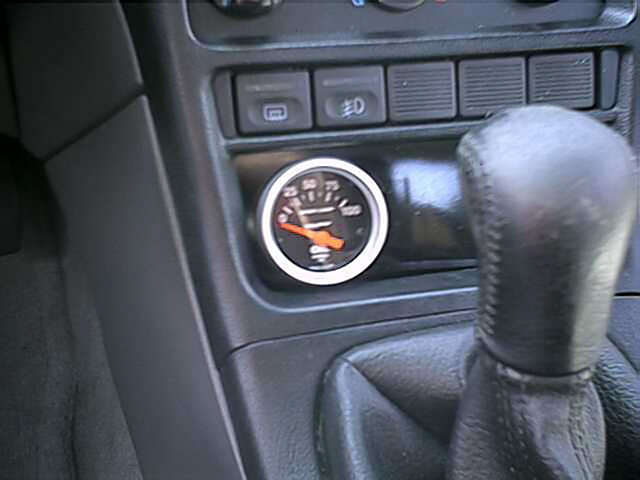 Interior view of a car's dashboard with a gauge and gear shifter