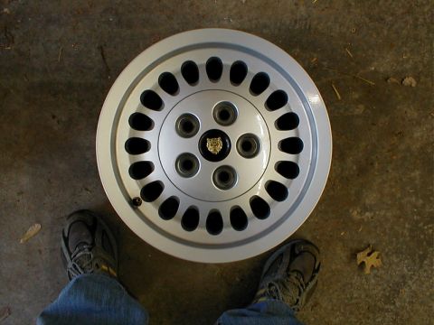 1994 Ford Bronco - A silver Jaguar wheel with a distinctive design multiple oval cutouts and a Jaguar emblem in the center is shown.