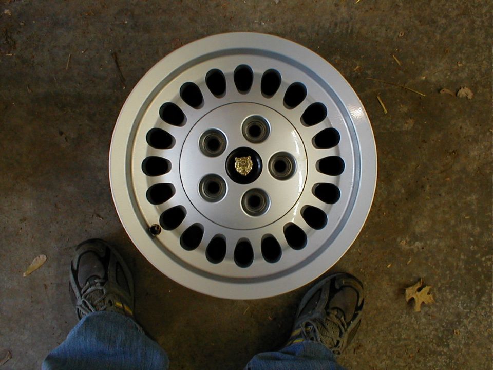 Silver Jaguar wheel with black oval cutouts and a Jaguar head center cap