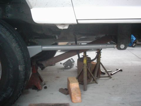 1978 Ford Bronco - Undercarriage of a white vehicle undergoing maintenance, supported by jack stands.