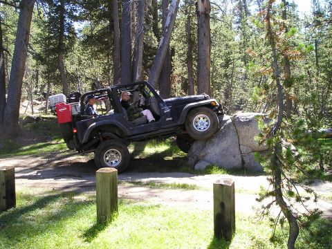 1989 Ford Bronco - Jeep Wrangler navigating a rock obstacle on an off-road trail.