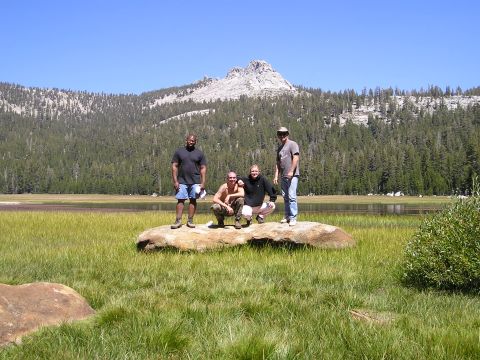 1989 Ford Bronco - A group poses on a rock during a trip to a mountainous region with a lake and dense forest.
