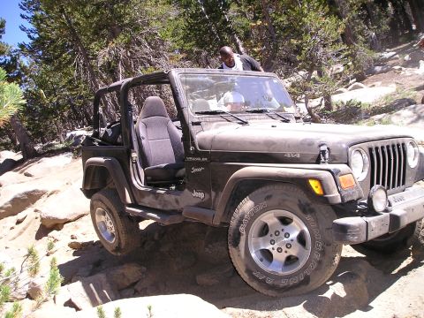 1989 Ford Bronco - Jeep Wrangler TJ navigating a challenging rocky terrain on an off-road trail.