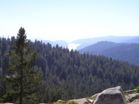 1989 Ford Bronco - A vast expanse of forested mountains stretches towards a hazy lake in the distance.