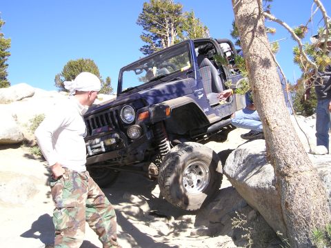 1989 Ford Bronco - A blue Jeep Wrangler is shown navigating a challenging rocky trail during an off-road excursion.