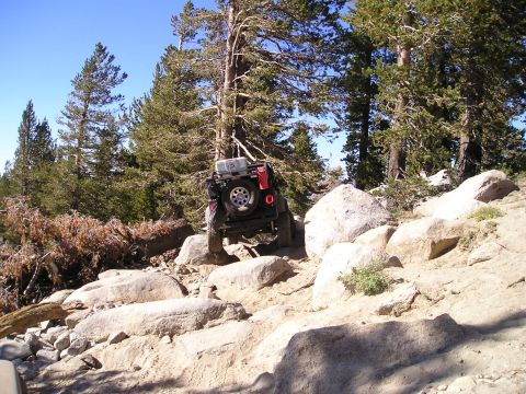 1989 Ford Bronco - A red Jeep Wrangler tackles a challenging rocky path during an off-road excursion.