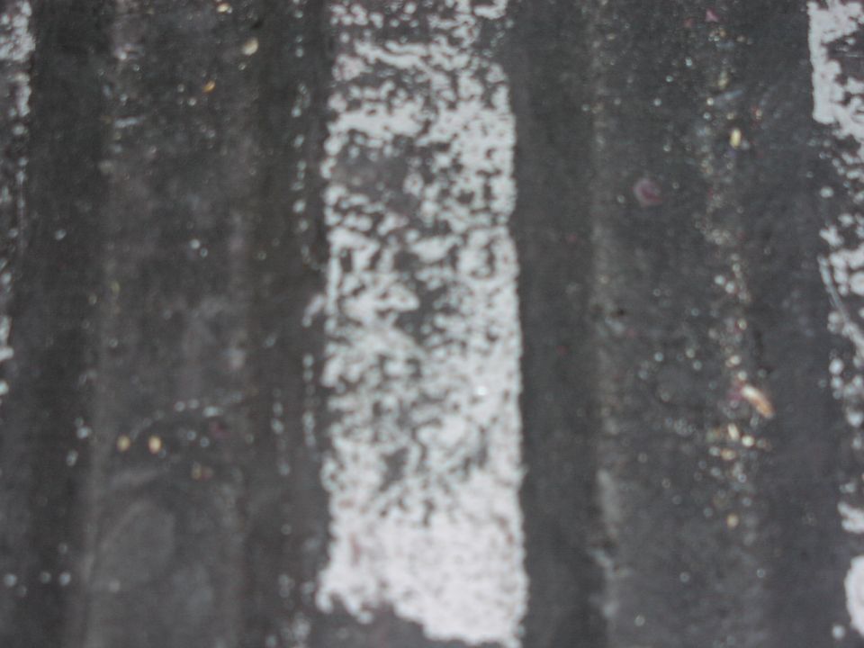 Close-up of a dark, ribbed surface with white paint splatters and faint numbers