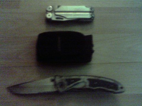 1990 Ford Ranger - A multi-tool, a black pouch, and a pocket knife are laid out on a wooden surface.