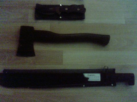 1990 Ford Ranger - An axe, a machete with its sheath, and a separate belt sheath are arranged on a wooden surface.