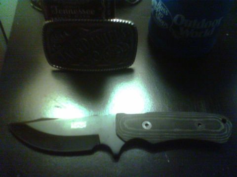 1990 Ford Ranger - A knife and a belt buckle are displayed on a reflective surface. The buckle has "Tennessee" visible.