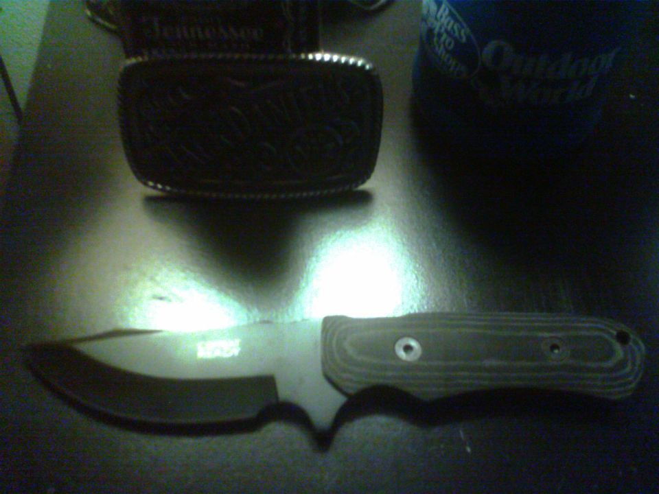 Knife with textured handle and a belt buckle with "Tennessee" text