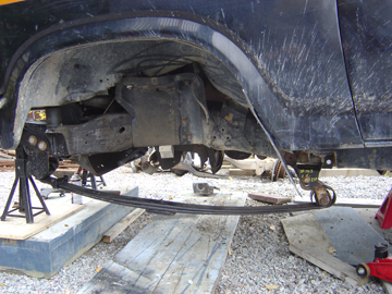 1986 Ford F-150 - The rear suspension of a truck is shown with leaf springs removed and the vehicle supported by jack stands.