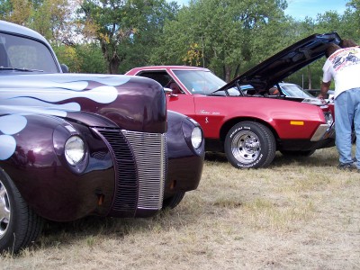 1972 Ford Ranchero - A red 1972 Ford Ranchero is displayed with its hood open, while a custom purple car with flame graphics is in the foreground.