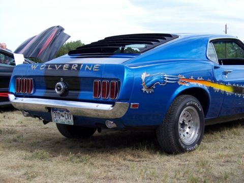 1972 Ford Ranchero - Blue 1969 Ford Mustang with custom Wolverine graphics and rear louvers is parked outdoors.