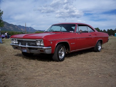 1972 Ford Ranchero - A classic red Chevrolet Impala coupe sits outdoors under a cloudy sky, with mountains visible in the distance.