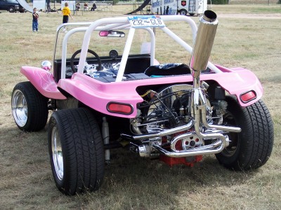 1972 Ford Ranchero - A custom pink dune buggy with a prominent exhaust pipe and exposed engine is parked on grassy terrain.