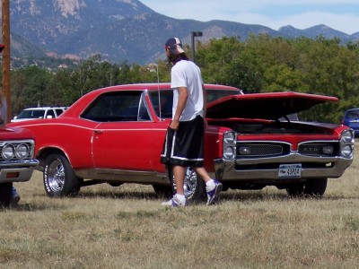 1972 Ford Ranchero - A red 1966 Pontiac GTO coupe is displayed with its hood open at a car show, with mountains visible in the distance.