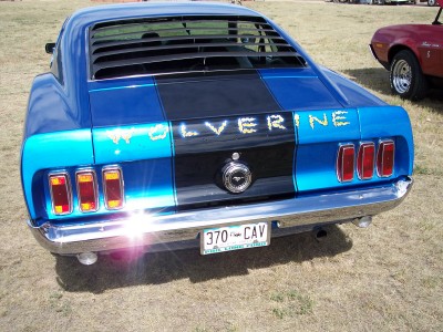 1972 Ford Ranchero - A blue Ford Mustang with a black stripe and custom 'WOLVERINE' lettering is parked next to another vehicle.