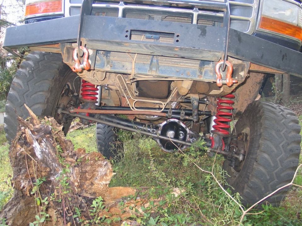 Front axle and suspension of a lifted 1992 Ford Bronco with red coil springs and large off-road tires