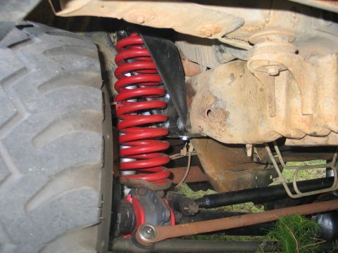 1995 Ford Bronco - Close-up view of a red coil spring suspension component on a vehicle's undercarriage.