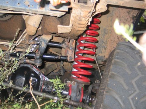 1995 Ford Bronco - Underneath view of a vehicle's suspension system with a red coil spring and tire.