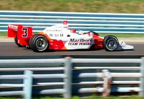 1979 Ford F-150 - A Marlboro Team Penske IndyCar races on a track, with blue and white barriers visible.