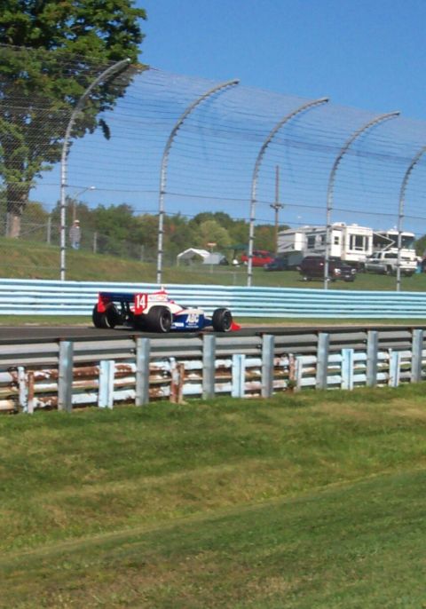 1979 Ford F-150 - An open-wheel race car with the number 14 is seen on a track with a fence and grassy embankment.