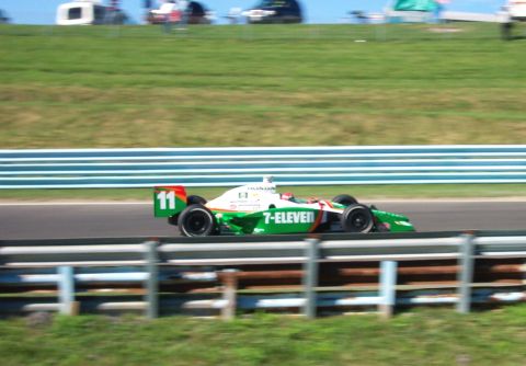 1979 Ford F-150 - A race car with 7-Eleven sponsorship speeds down the track, number 11 visible on the rear wing.