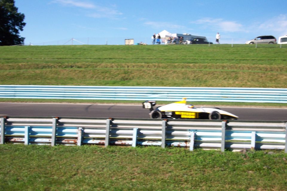 Open-wheel race car with yellow and white body on a track