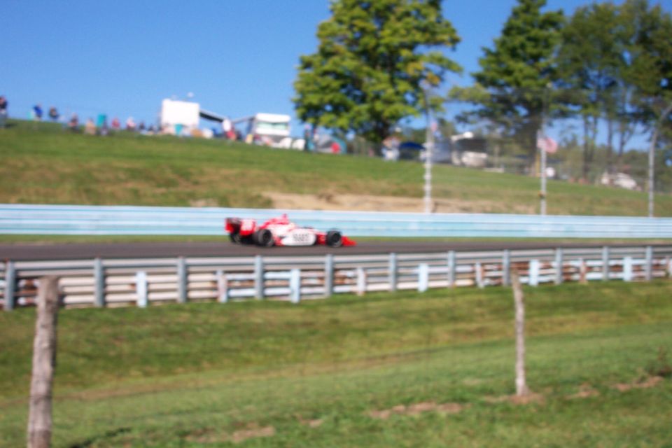 Open-wheel race car on a track with spectators in the background
