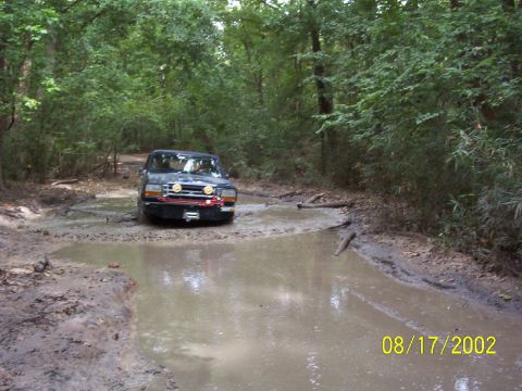 1991 Ford Bronco - Ford Bronco navigating a muddy trail in a wooded area.