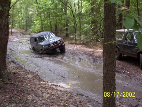 1991 Ford Bronco - Two Ford Broncos navigating a challenging muddy off-road course.