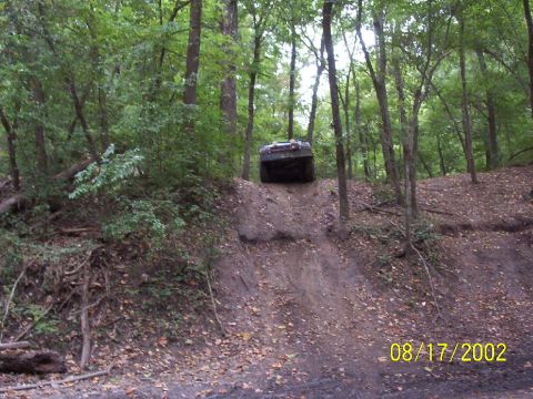 1991 Ford Bronco - An off-road vehicle navigates a steep incline in a wooded area, captured on August 17, 2002.