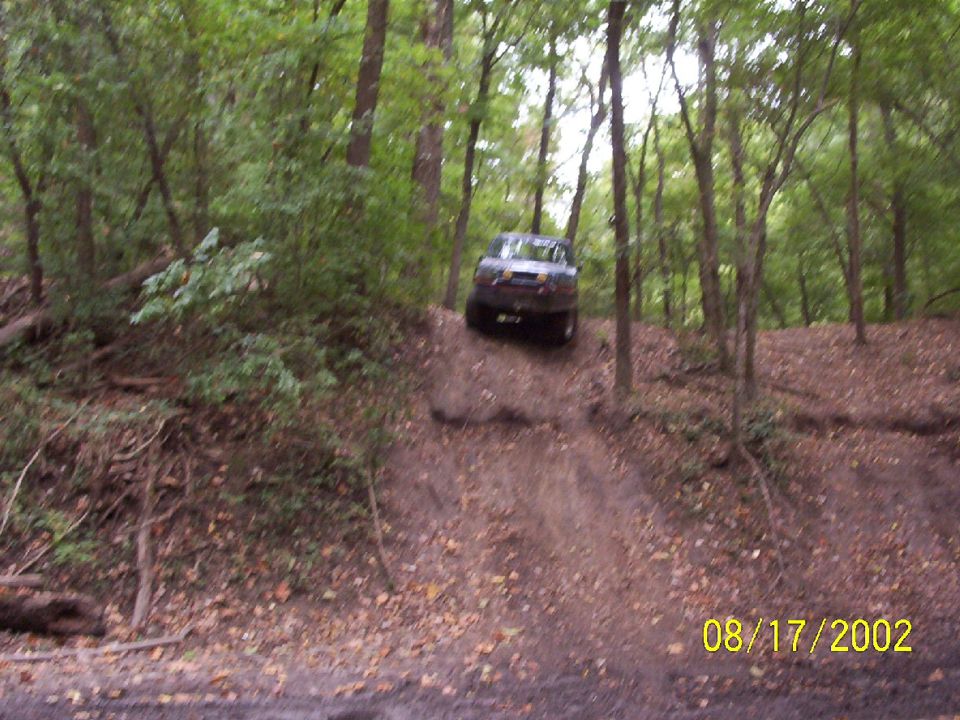 Dark SUV driving downhill on a dirt path in a forest