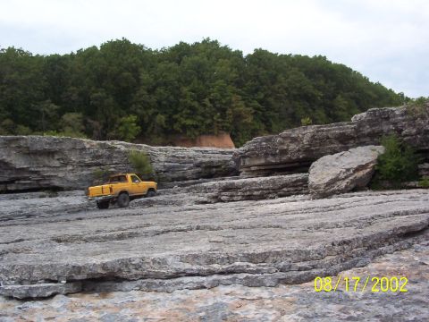 1991 Ford Bronco - A yellow pickup truck navigates a rocky, outdoor landscape.