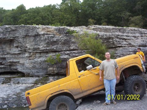 1991 Ford Bronco - A yellow off-road SUV is parked on a rocky terrain with two people nearby.