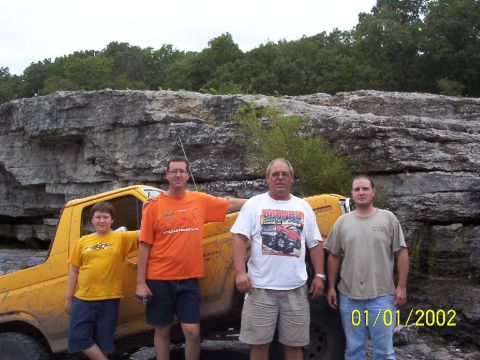 1991 Ford Bronco - Four men pose with a yellow Ford Bronco in a rocky, outdoor setting.