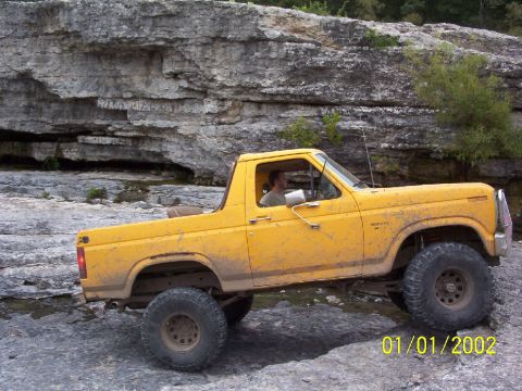 1991 Ford Bronco - Yellow Ford Bronco navigating rocky terrain off-road.