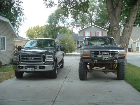 2006 Ford F-350 - Two Ford trucks are parked in a driveway. The truck on the left is a 2006 Ford F-350, while the truck on the right appears to be an older m…