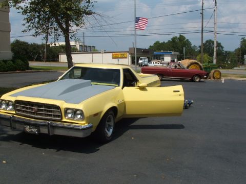 1966 Ford Ranchero - Yellow 1970s Ford Ranchero with aftermarket hood and open door, parked next to a red pickup.