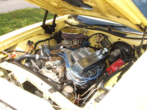 1966 Ford Ranchero - The engine bay of a yellow vehicle reveals a powerful Ford Racing V8 engine with custom components.