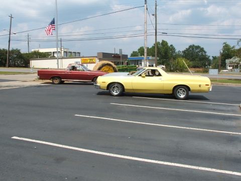 1966 Ford Ranchero - Two Ford Rancheros, one yellow and one red, are parked in a lot under a cloudy sky.